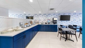 A modern kitchen with blue cabinets, a marble countertop, and a flat-screen TV mounted on the wall. - Executive Residency by Best Western Victorville (Victorville)