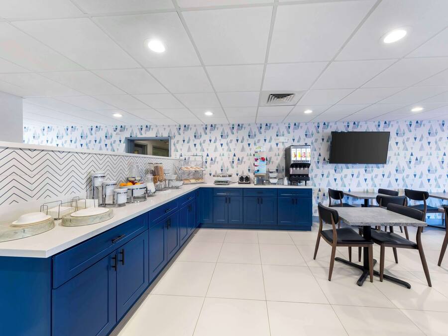 Una cocina moderna con armarios azules, encimera de mármol y televisor de pantalla plana montado en la pared.