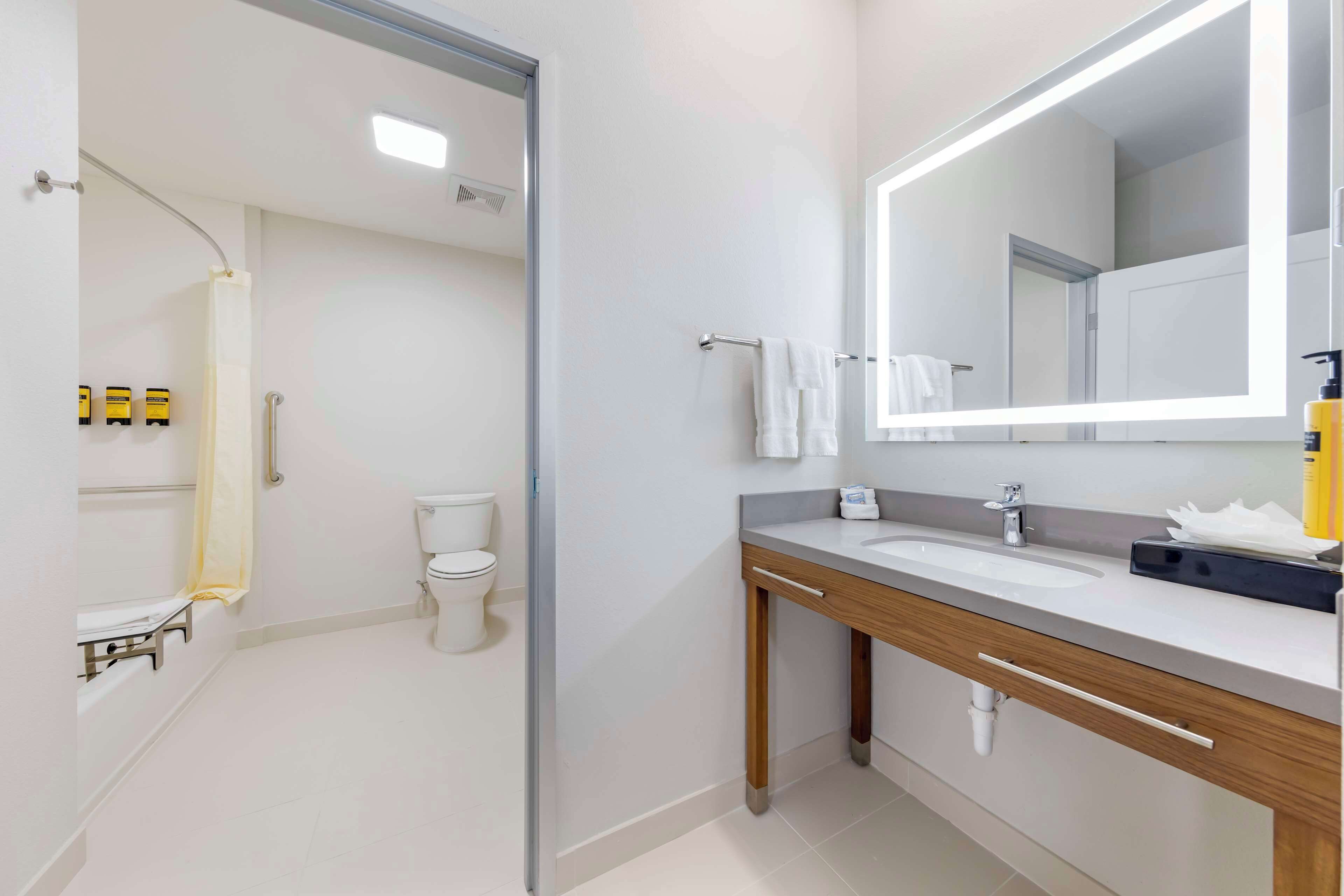 Ein modernes Badezimmer mit großem Spiegel, Waschbecken und Toilette.