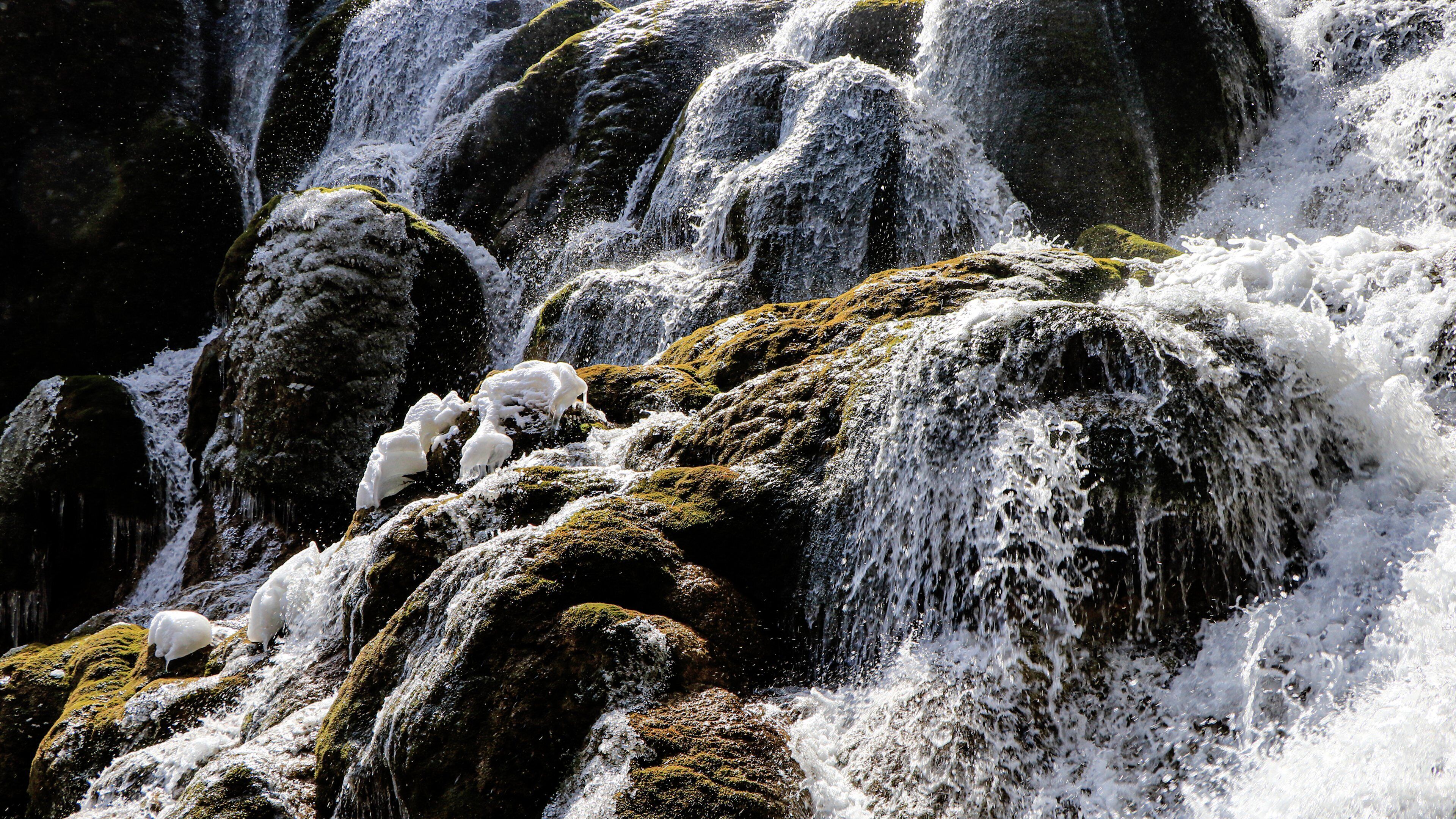 Une cascade d’eau se déversant sur des rochers couverts de mousse.