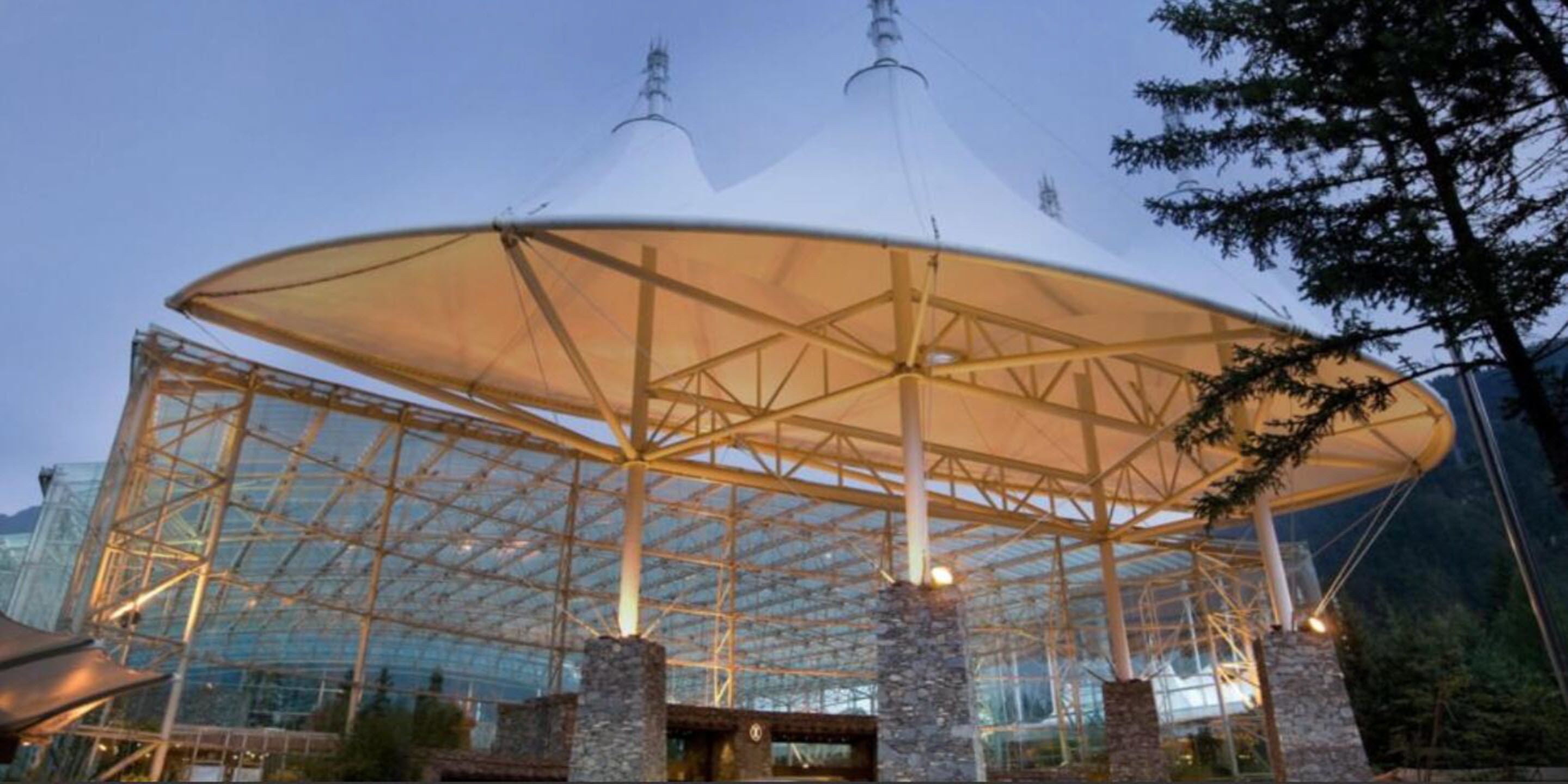 Una gran estructura de vidrio con un espacio central abierto y pilares de piedra.