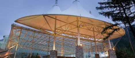 Una gran estructura de vidrio con un espacio central abierto y pilares de piedra.
