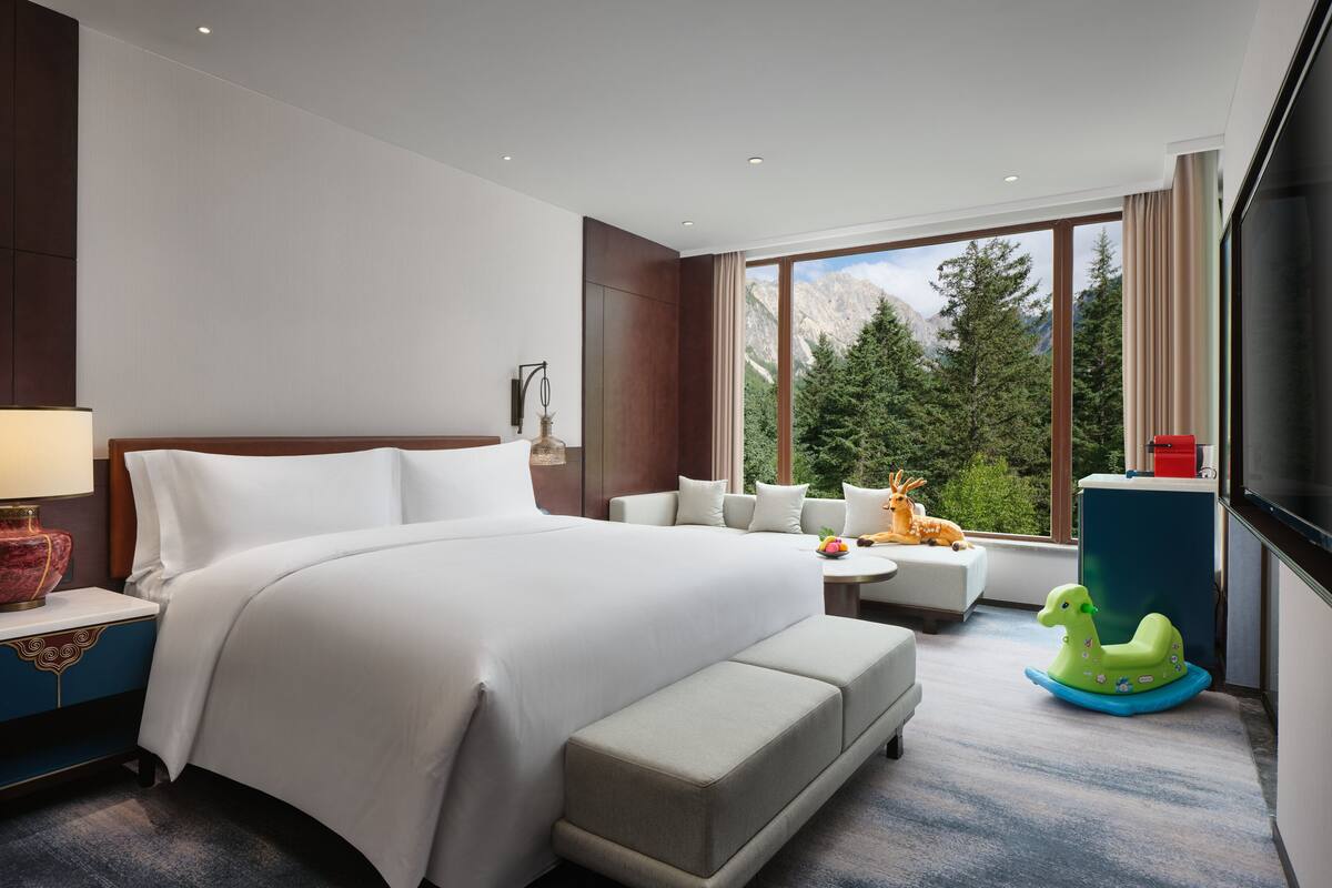 Une chambre d’hôtel moderne avec un grand lit, un canapé, une petite table et un téléviseur.