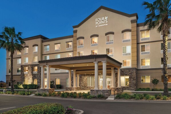 Un hotel con entrada cubierta, varios pisos y fachada de piedra.