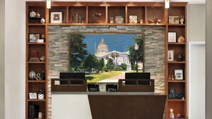 A lobby with a large painting of a capitol building, wooden shelving with various items, and a reception desk. - Four Points by Sheraton Sacramento International Airport (Sacramento)
