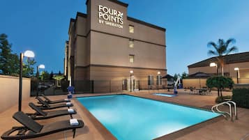 Ein Hotel namens 'Four Points by Sheraton' mit Schwimmbad, Liegestühlen und Außenbereich.