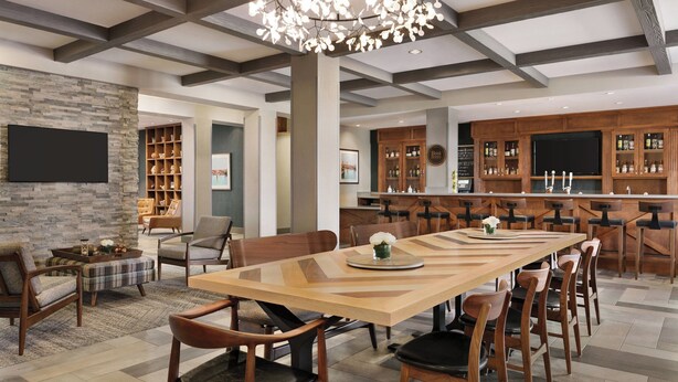 A spacious dining area with a long wooden table, surrounded by chairs, and a modern chandelier. - Four Points by Sheraton Sacramento International Airport (Sacramento)