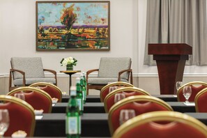 A conference room with two chairs facing a table, a podium, and a painting on the wall. - Four Points by Sheraton Sacramento International Airport (Sacramento)