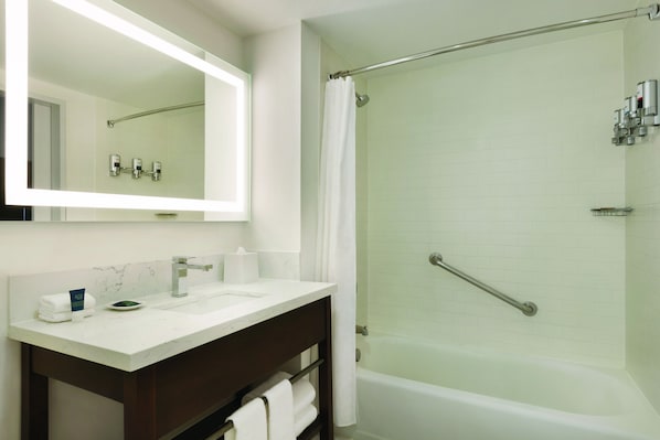 A bathroom with a white sink, a mirror, a shower with a glass door, and a bathtub. - Four Points by Sheraton Sacramento International Airport (Sacramento)