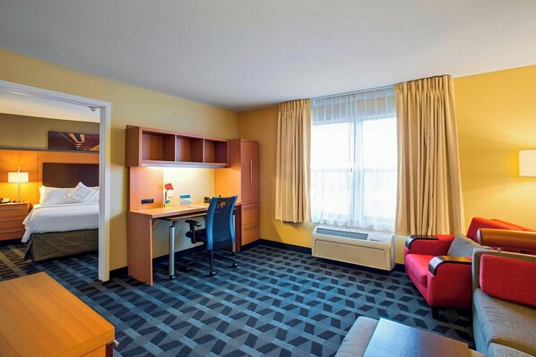 Una habitación de hotel con cama, escritorio, silla y sofá rojo.