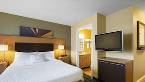 Habitación de hotel con una cama grande, lámparas de noche, un televisor de pantalla plana y un mueble de madera.