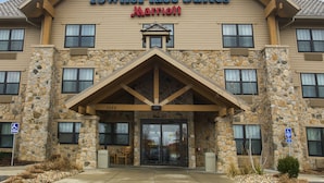 Un hotel con fachada de piedra, una entrada destacada con porche cubierto y un letrero que dice "TownePlace Suites Marriott".