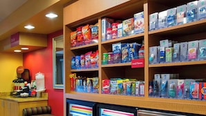 Un bar de aperitivos con estantes llenos de diversas botanas y bebidas, una zona de estar y un refrigerador con bebidas.