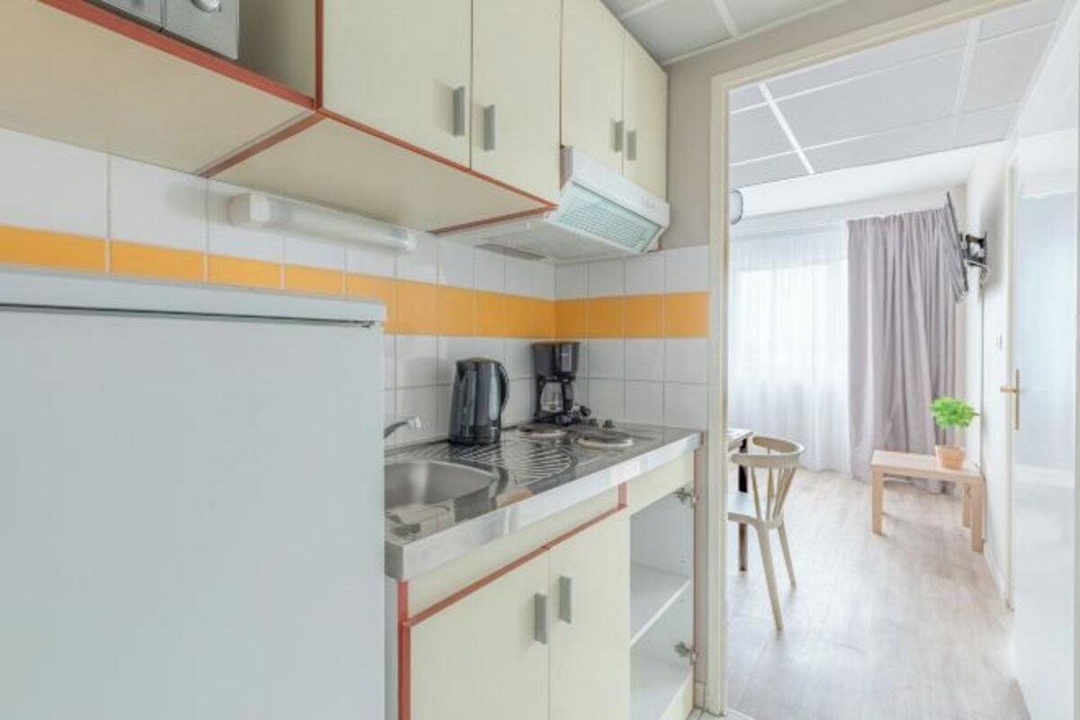 Une cuisine compacte équipée d’une cuisinière, d’un évier et d’un petit coin repas avec une table et des chaises.