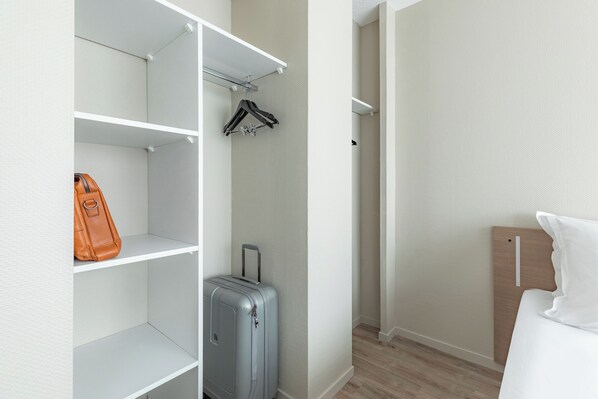 A hotel room with a wardrobe, a suitcase, and a hanging coat rack.