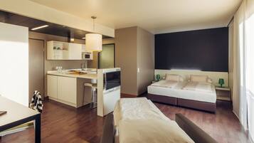 Una habitación de hotel moderna con kitchenette, una cama y un escritorio.