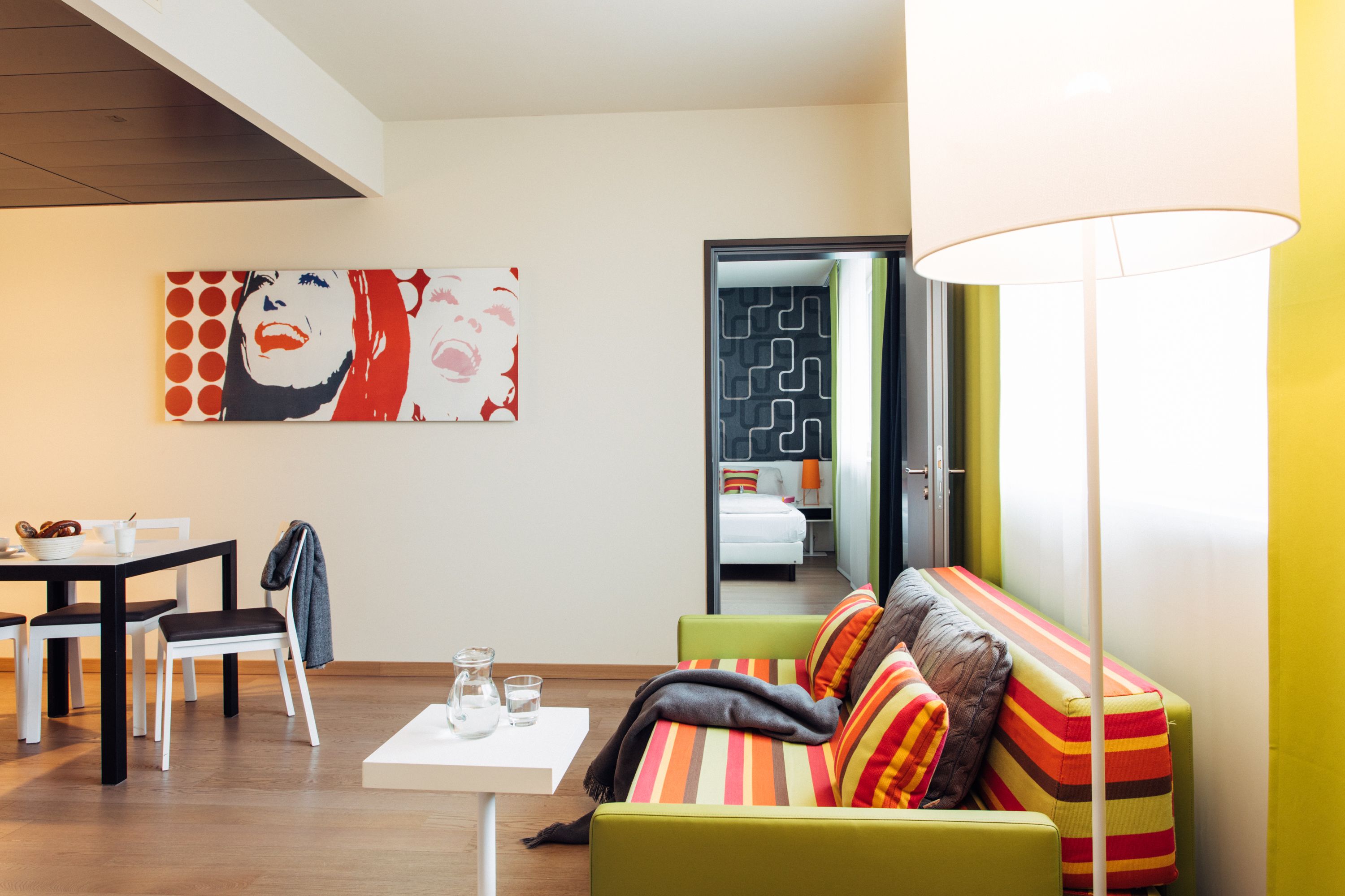 A modern living room with a green sofa, a white coffee table, and a painting on the wall.