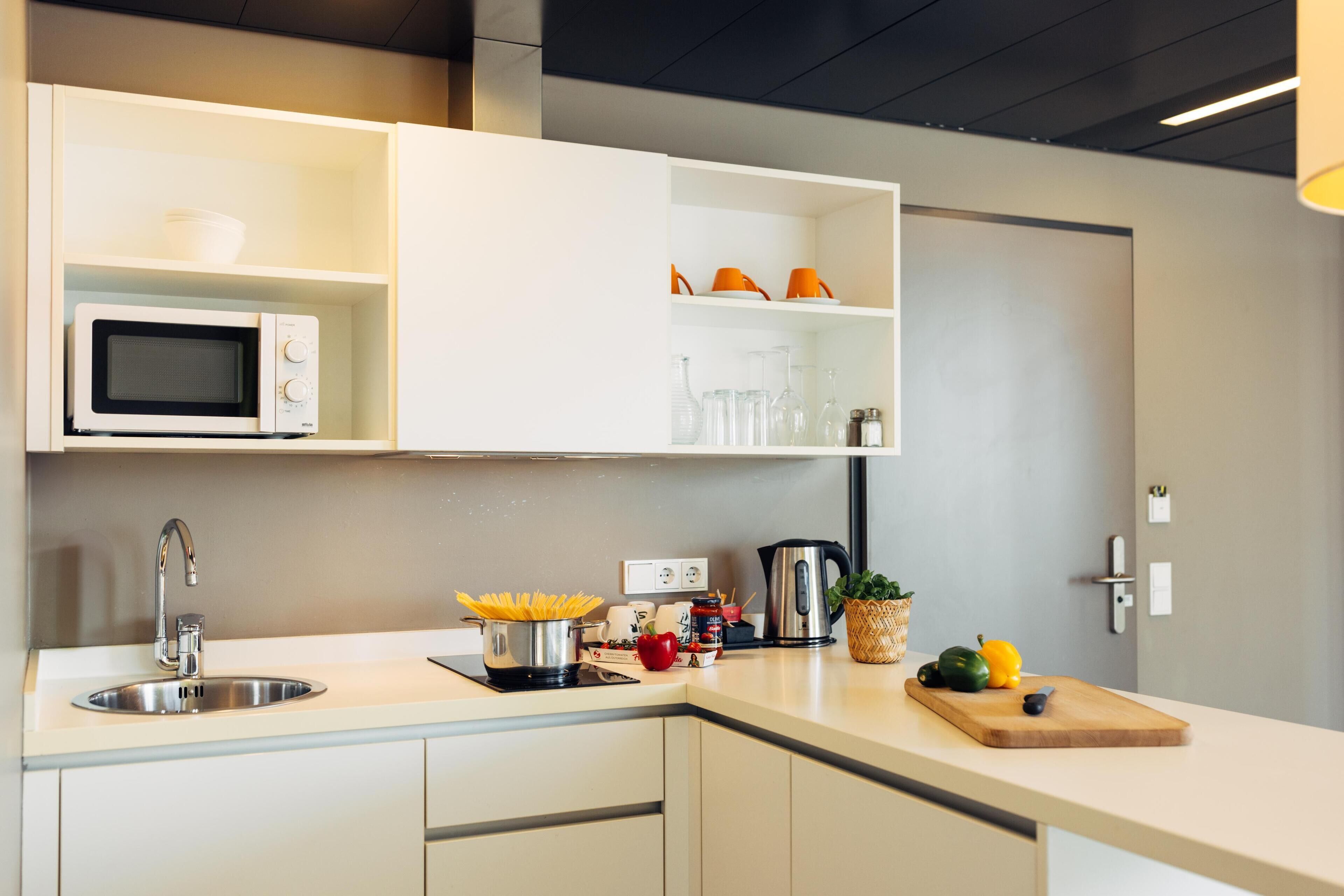 Una cocina moderna con microondas integrado, un lavamanos y una tabla de cortar de madera.