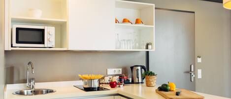 Una cocina moderna con microondas integrado, un lavamanos y una tabla de cortar de madera.