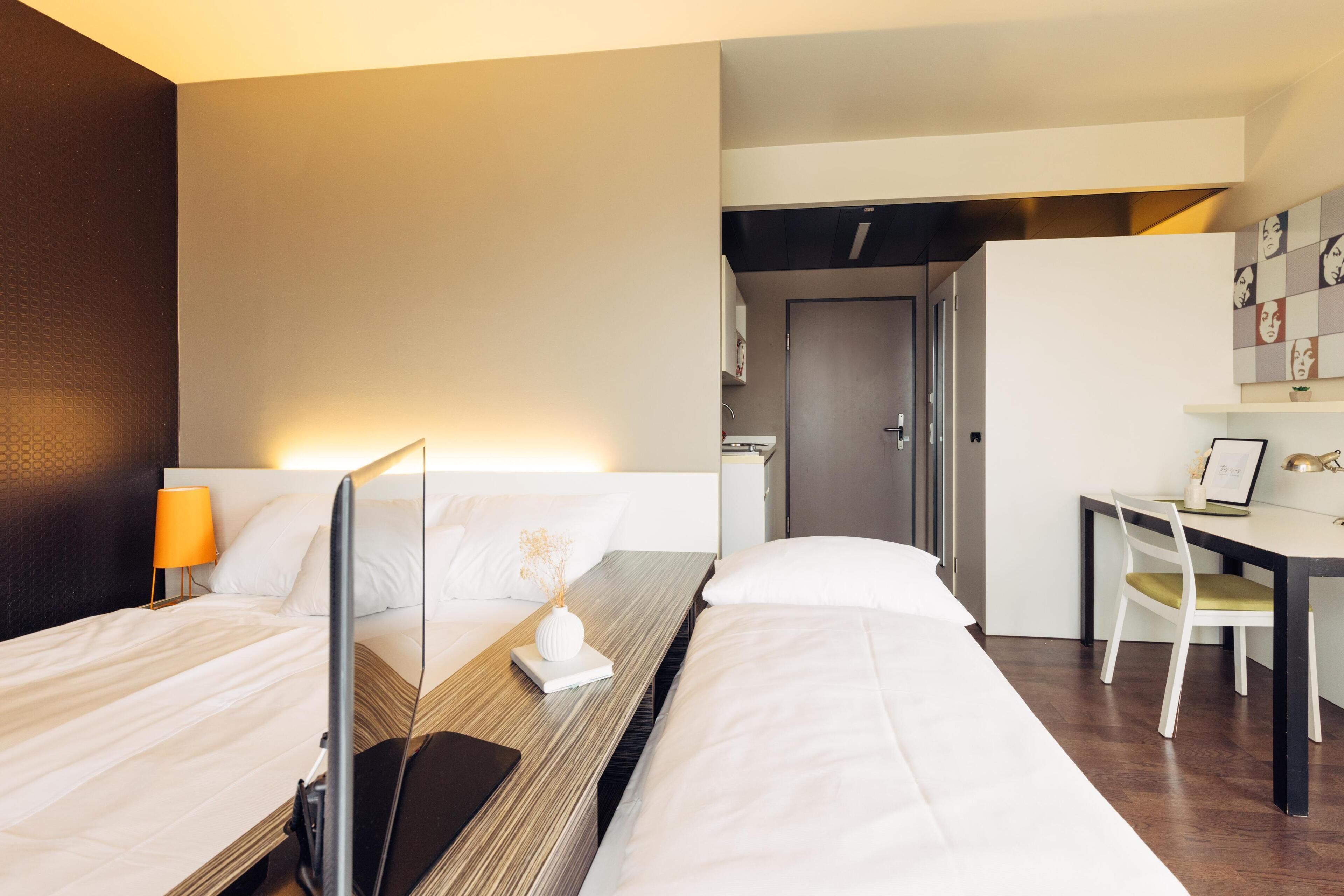 Habitación de hotel con dos camas, un escritorio y una silla.