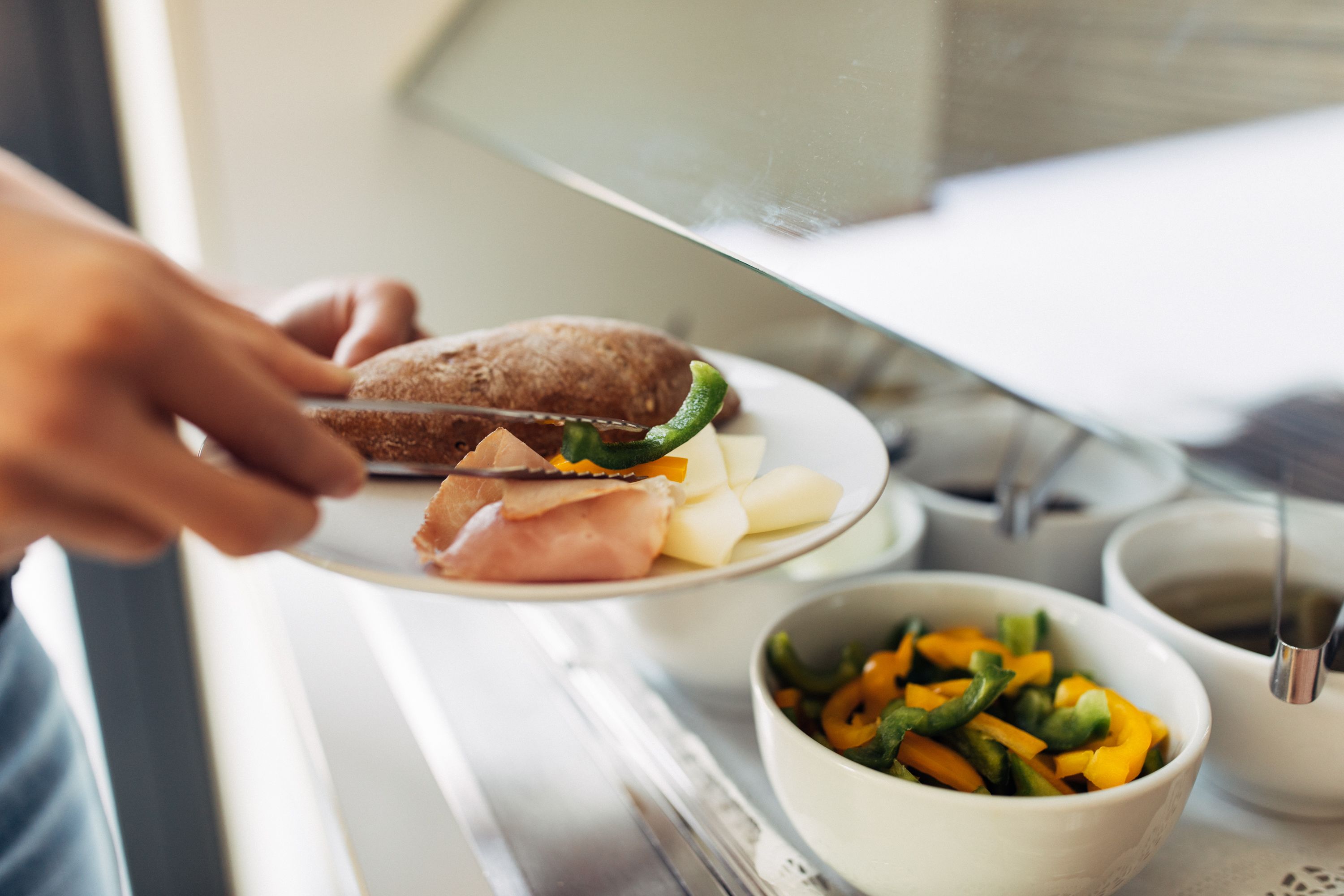 A person cutting a sandwich on a plate.