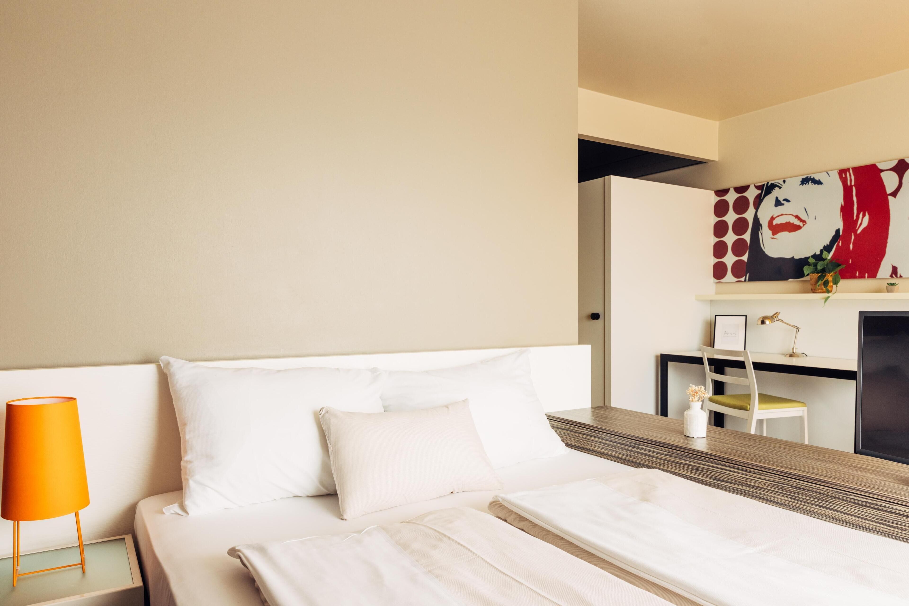 Una habitación de hotel con una cama, una mesita de noche, un escritorio y una silla.