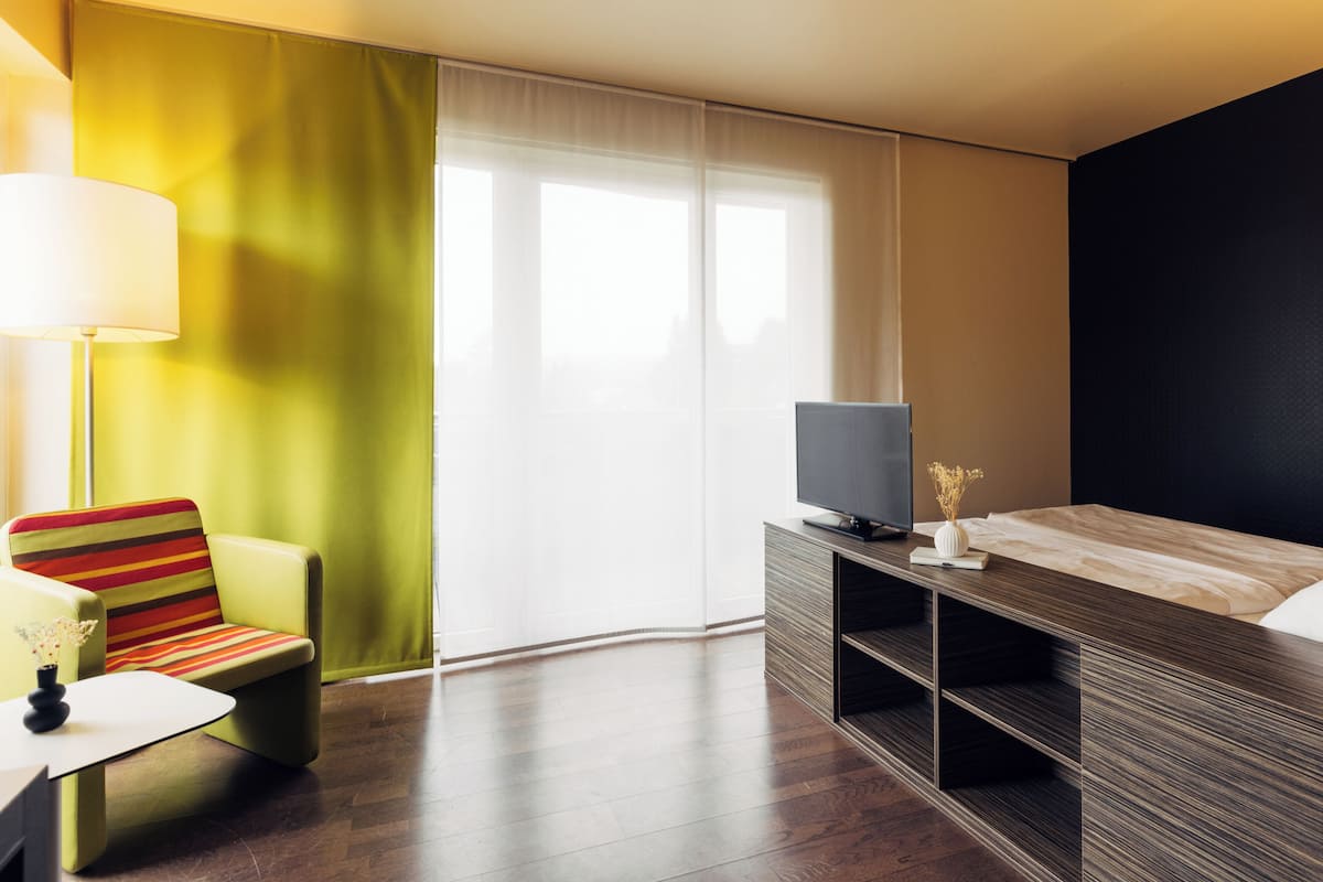 A hotel room with a bed, a TV, a chair, and a table.