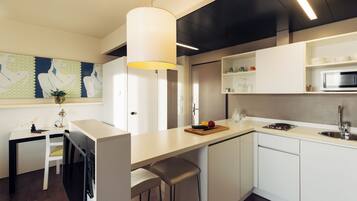 A modern kitchen with white cabinetry, a central island with stools, a microwave, and a hanging light fixture.