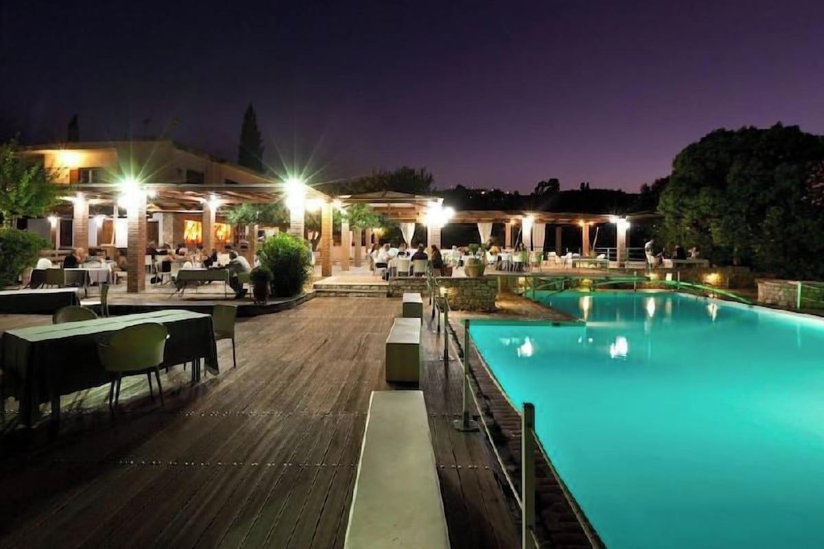 Un espace extérieur avec une piscine, des tables et des chaises, une terrasse en bois.