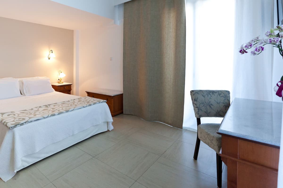 Een hotelkamer met een bed, nachtkastjes, een bureau en een stoel.