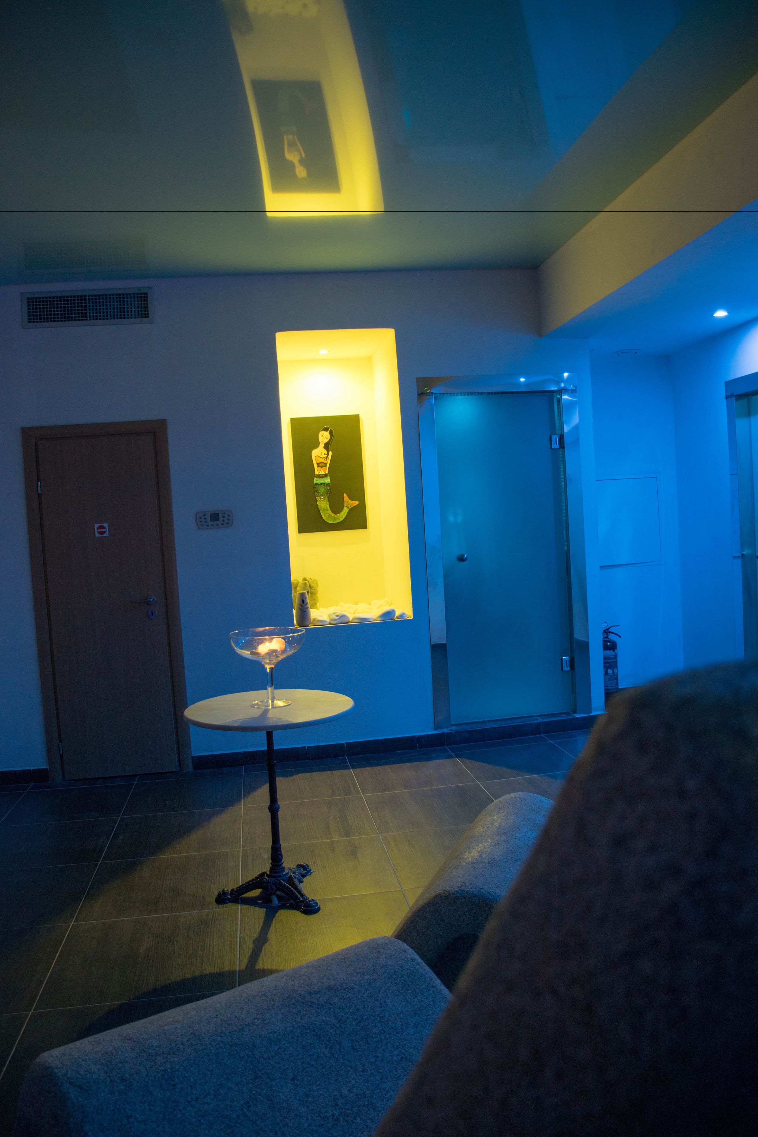 A hotel lobby with a reception desk, a wall-mounted artwork, and a door to a private room.