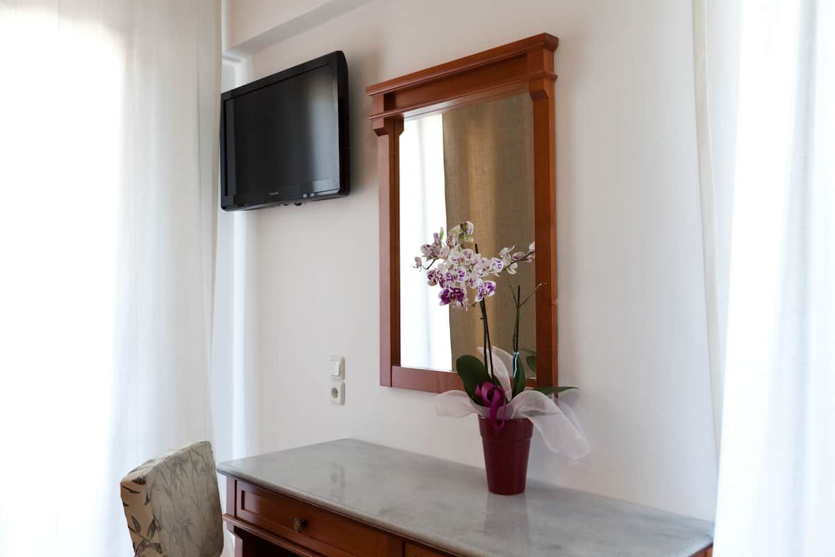 Een badkamer met een marmeren aanrecht, een potorkidee, een houten stoel en een tv aan de muur.