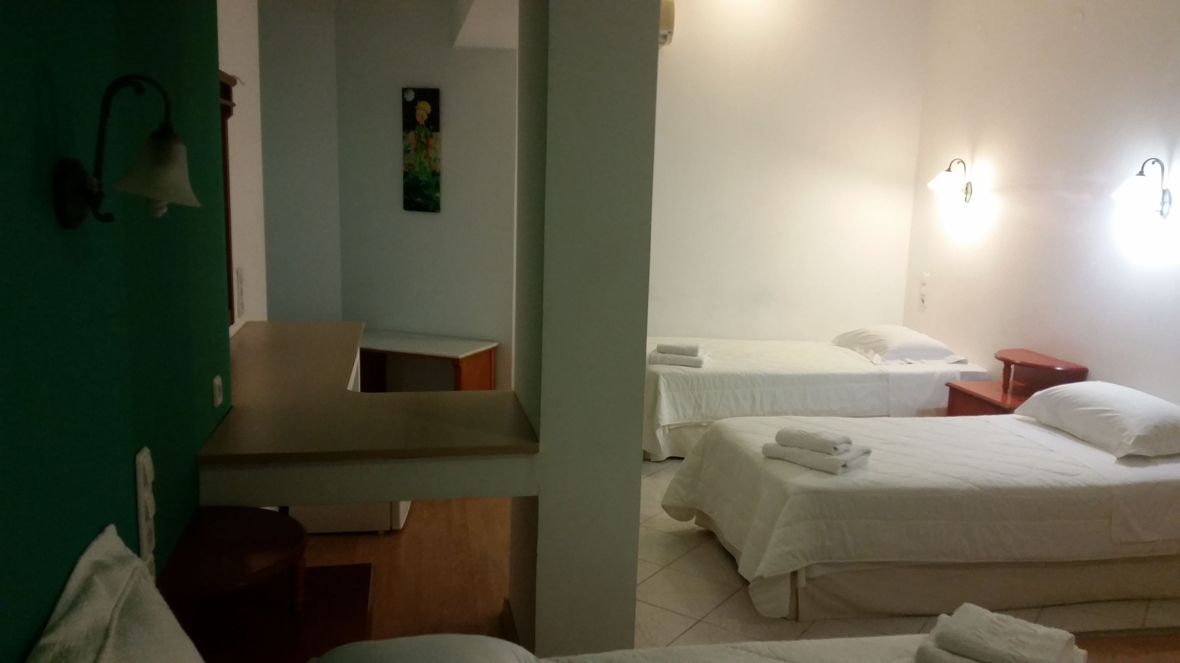 Une chambre d’hôtel avec deux lits, un mur vert et un tableau.