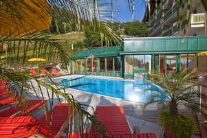 Una piscina al aire libre, sombrillas, sillones reclinables de piscina