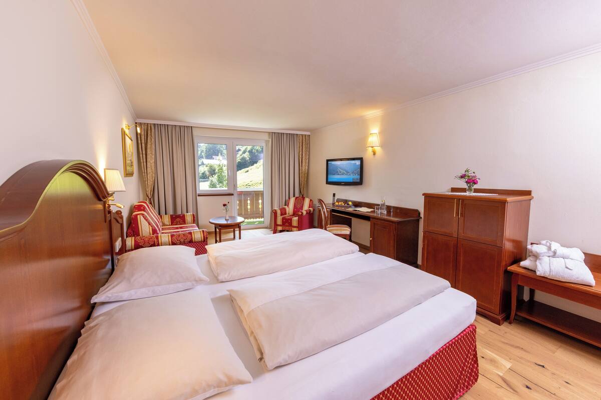 Une chambre d’hôtel avec un grand lit, un bureau, une chaise, une télévision et une vue sur l’extérieur.