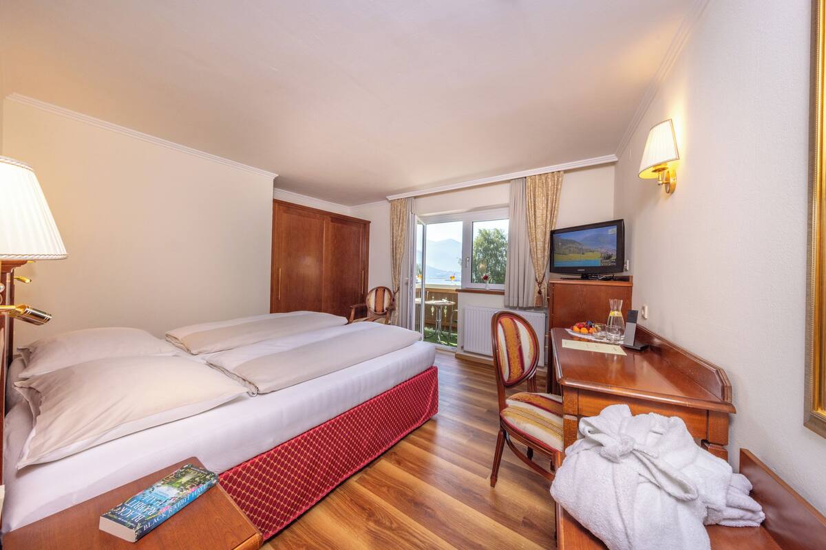 Une chambre d’h ôtel équipée d’un lit, d’un bureau, d’une chaise, d’une télévision et d’une fenêtre avec des rideaux.