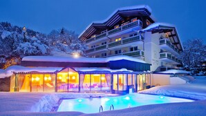 Ein mehrstöckiges Hotel mit einem beheizten Außenpool und einer überdachten Lounge-Bereich.