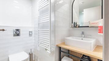 A modern bathroom with a white toilet, a white sink, a towel rack, and a mirror.