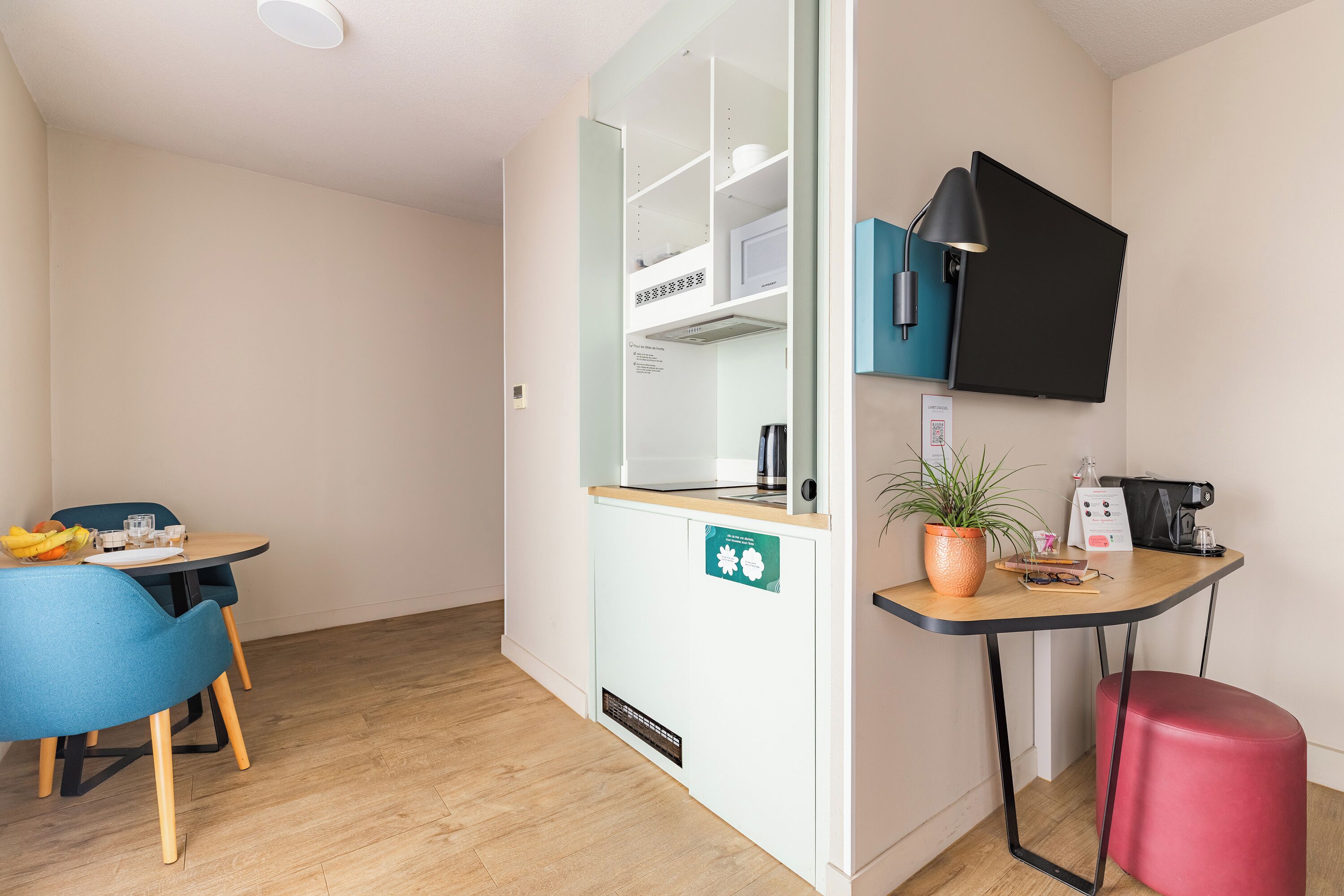 A compact kitchenette with a microwave, coffee maker, and a small table with chairs.