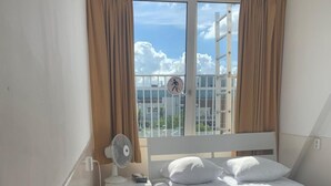 A hotel room with a bed, bedside table, chair, and a window with curtains.