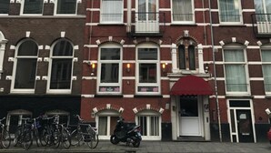 A row of red brick townhouses with white window frames and a red awning over the entrance.