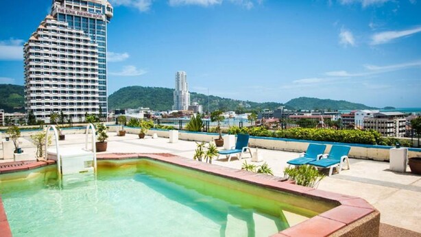 Zona d'una piscina al terrat amb gandules i vista als edificis i turons circumdants.