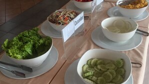 Un bufet ple de diferents plats, incloent-hi amanida, rodanxes de pepino i un bol de sopa.