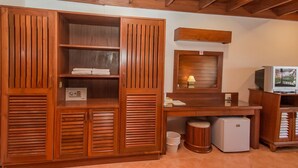 Habitació amb mobles de fusta, un escriptori, una televisió i un frigorífic petit.