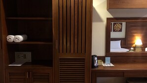 Habitació d'hotel amb escriptori de fusta, llit amb capçalera, tauleta de nit amb làmpada, safata de recollida de residus i calefactor fixat a la paret.