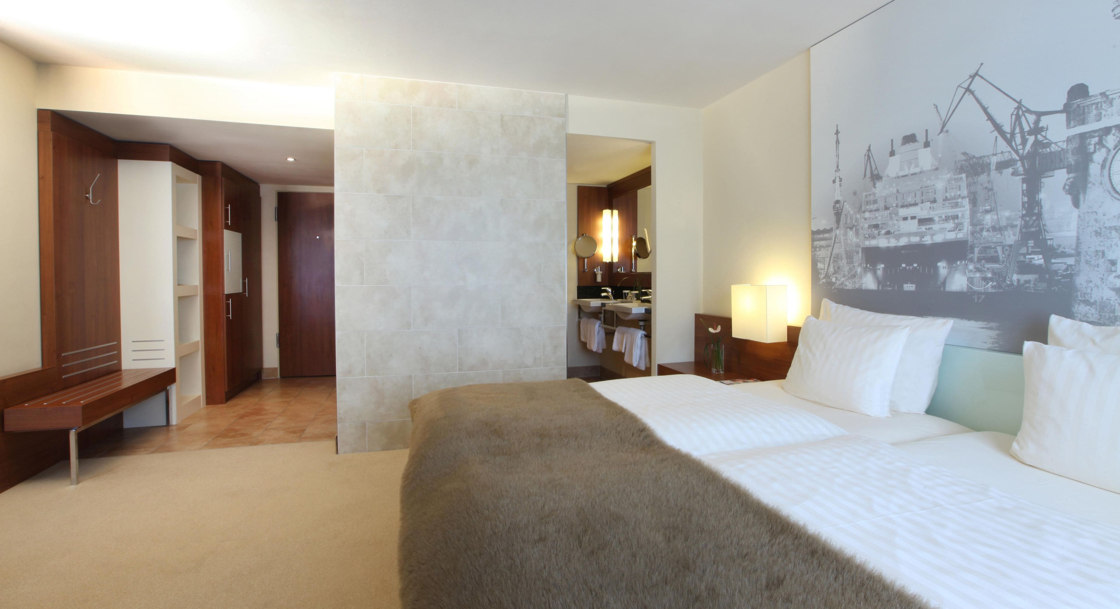 Ein Hotelzimmer mit einem Bett, einem Badezimmer und einem Flur, der zu einem weiteren Zimmer führt.