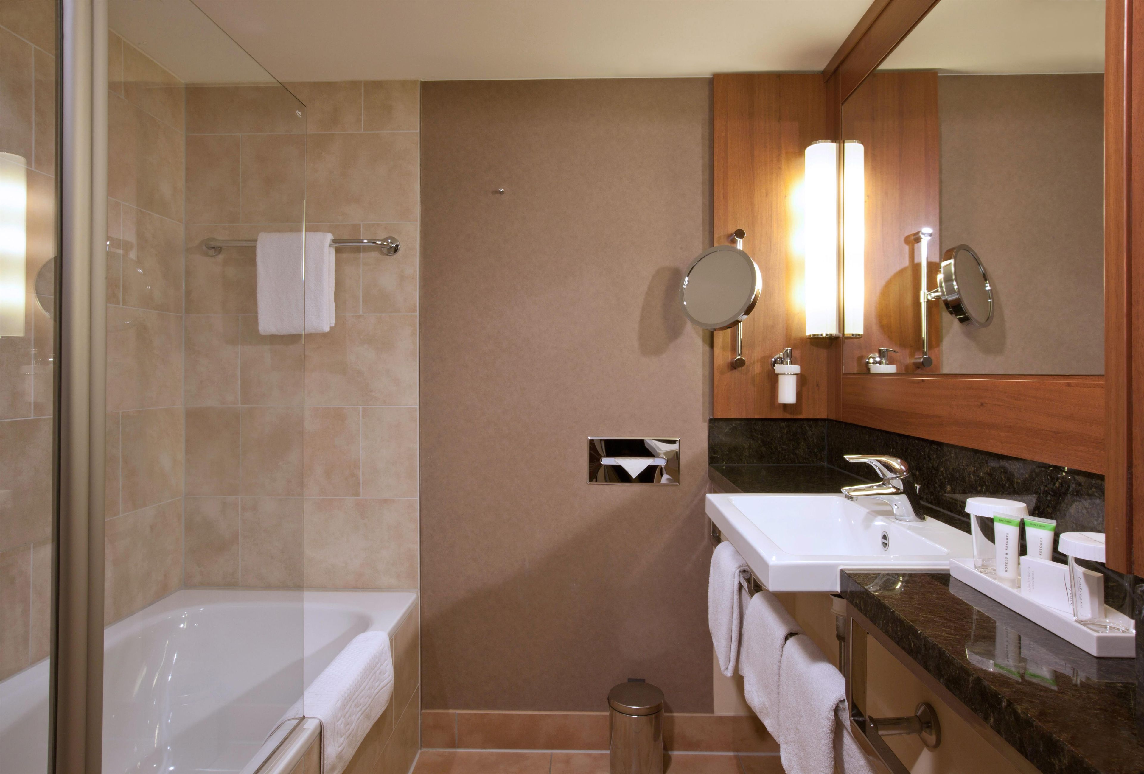 Une salle de bain moderne avec une baignoire, deux lavabos, un miroir et des toilettes.