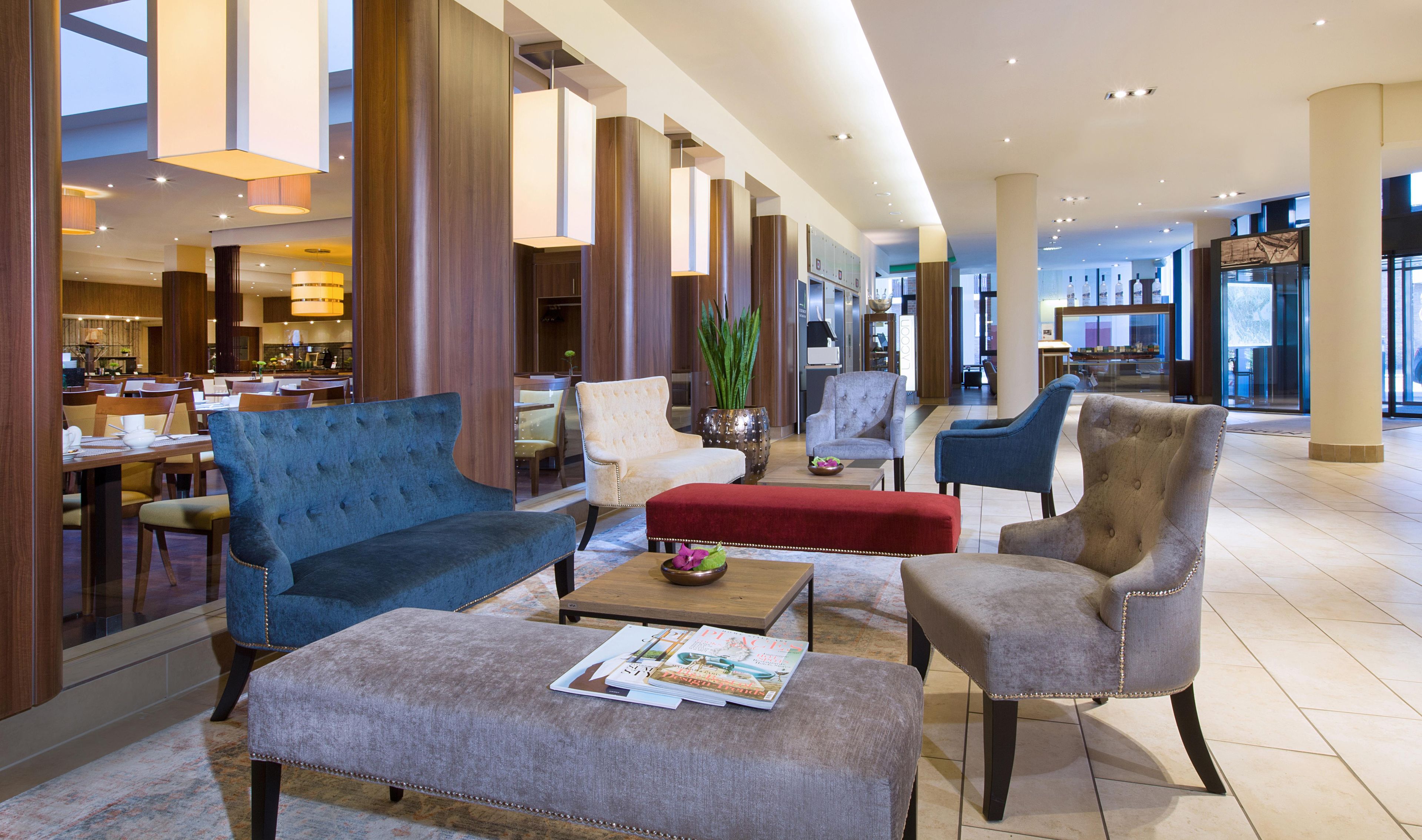 Een hotel lobby met een zithoek met banken en fauteuils, een bijzettafeltje en een tijdschrift.
