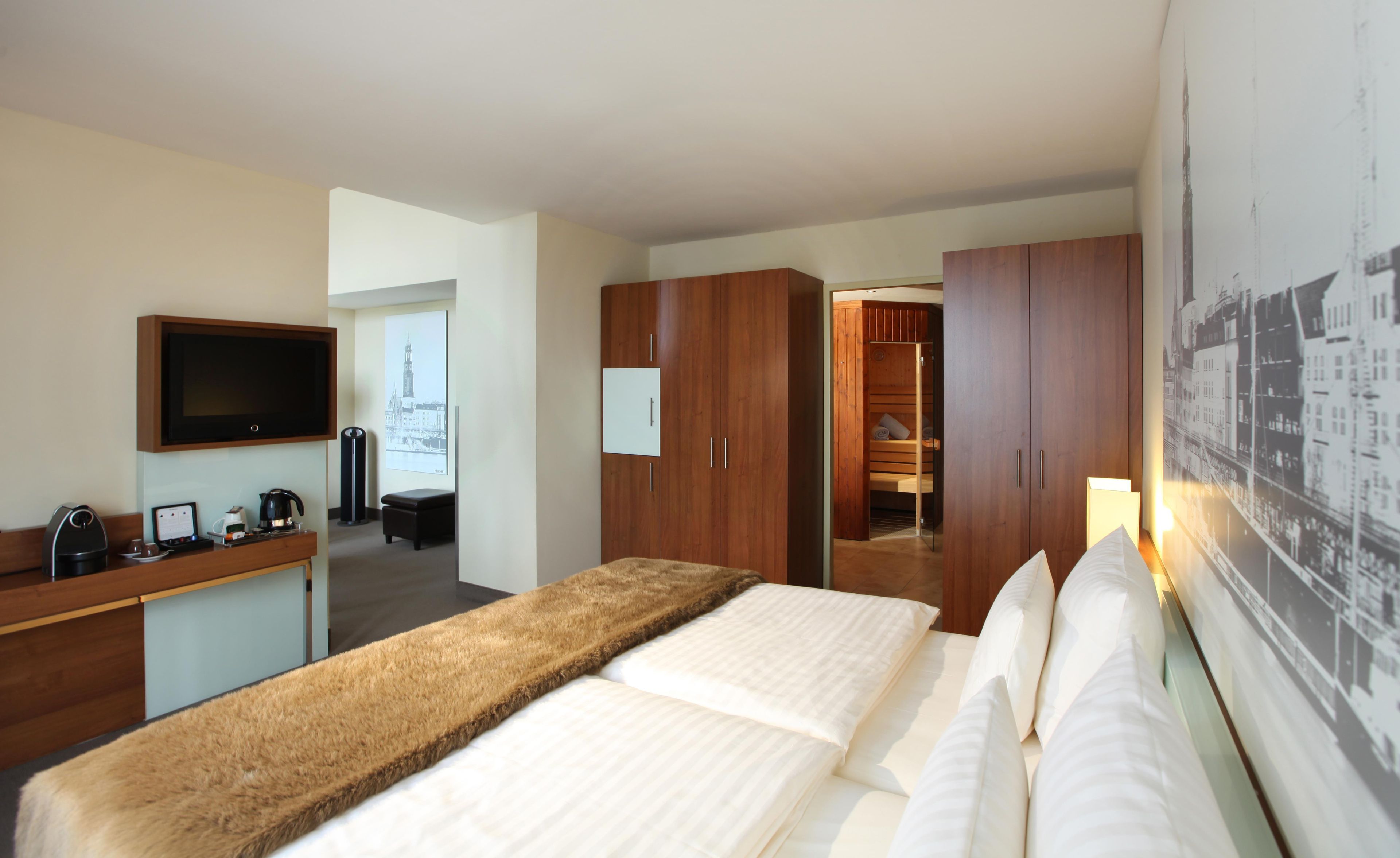 Ein Hotelzimmer mit Bett, Schreibtisch, Kaffeemaschine, Fernseher und Kleiderschrank.