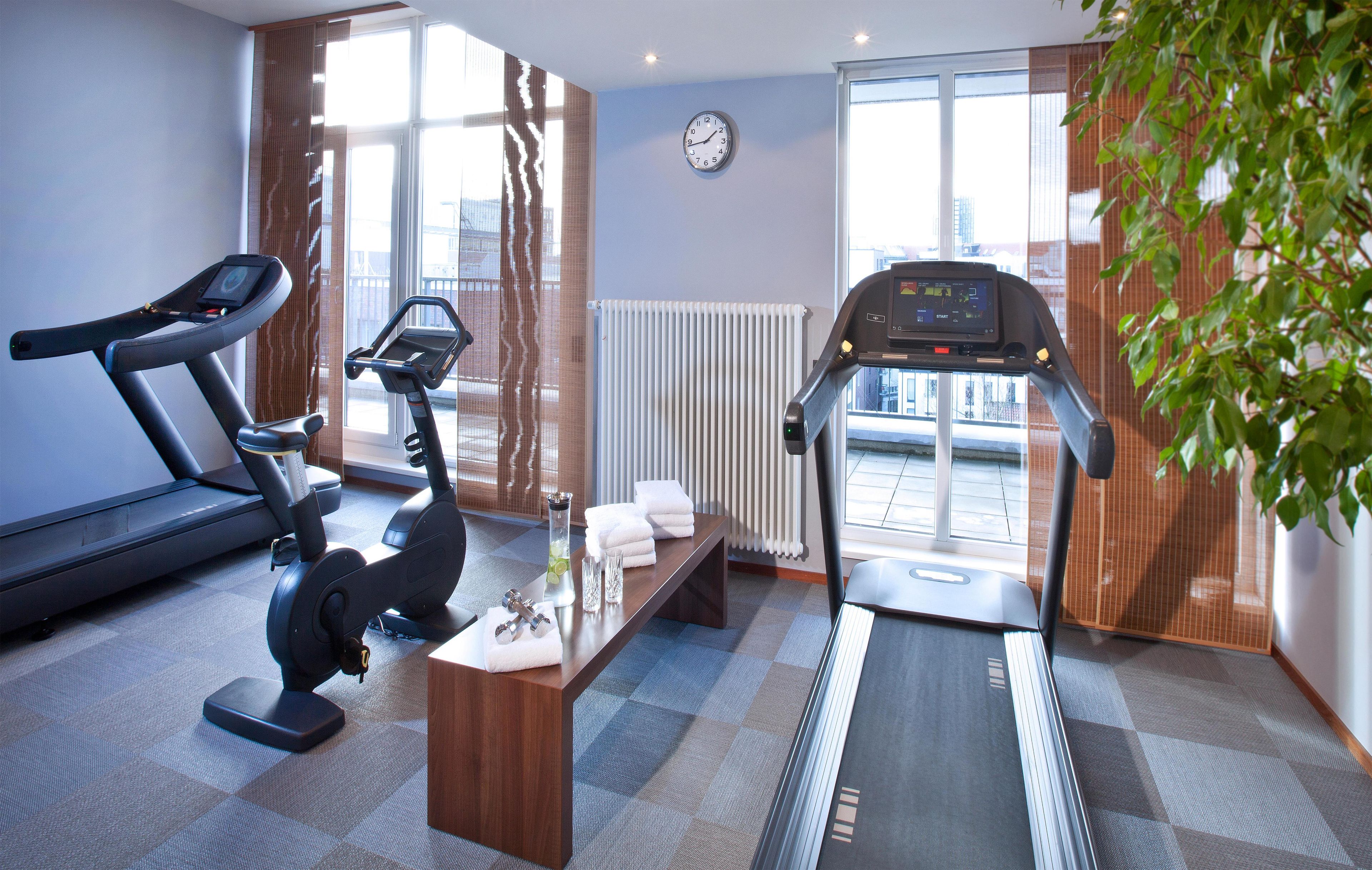 Un gimnasio con equipamiento de ejercicio, un reloj y una ventana con vistas.